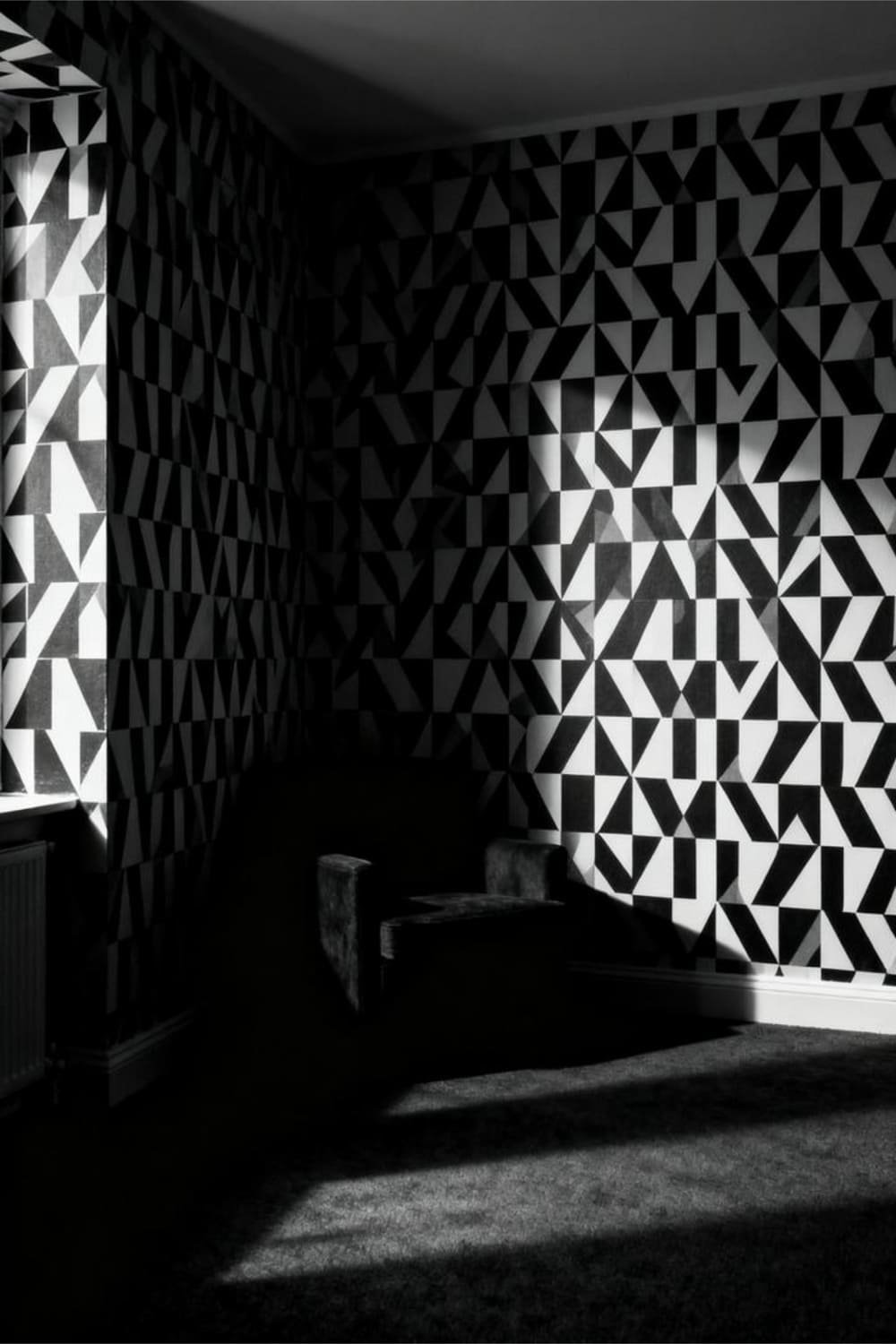 Low-light room featuring high-contrast black-and-white wallpaper that creates harsh visual shadows.