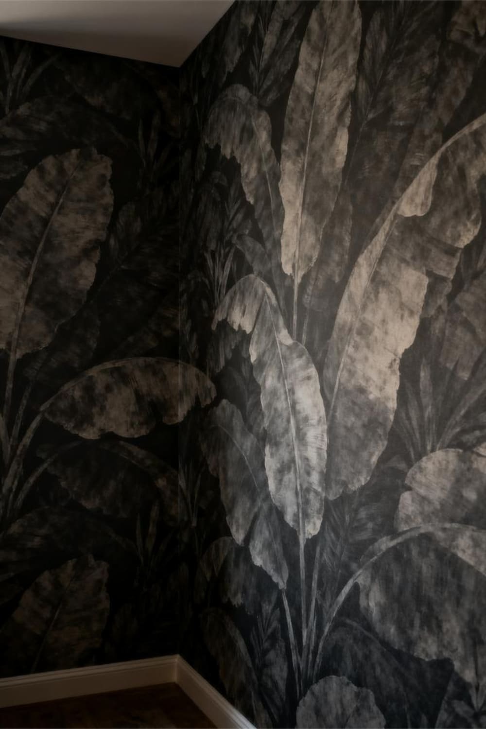 Interior showing oversized botanical wallpaper with large shapes that overwhelm a dim room.