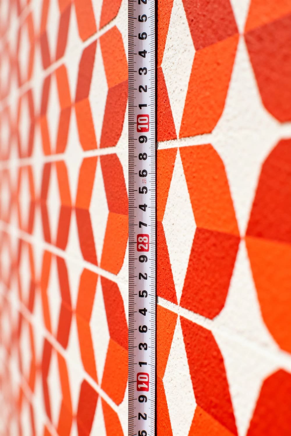Wallpaper with visible repeating pattern and measuring tape showing pattern repeat distance.