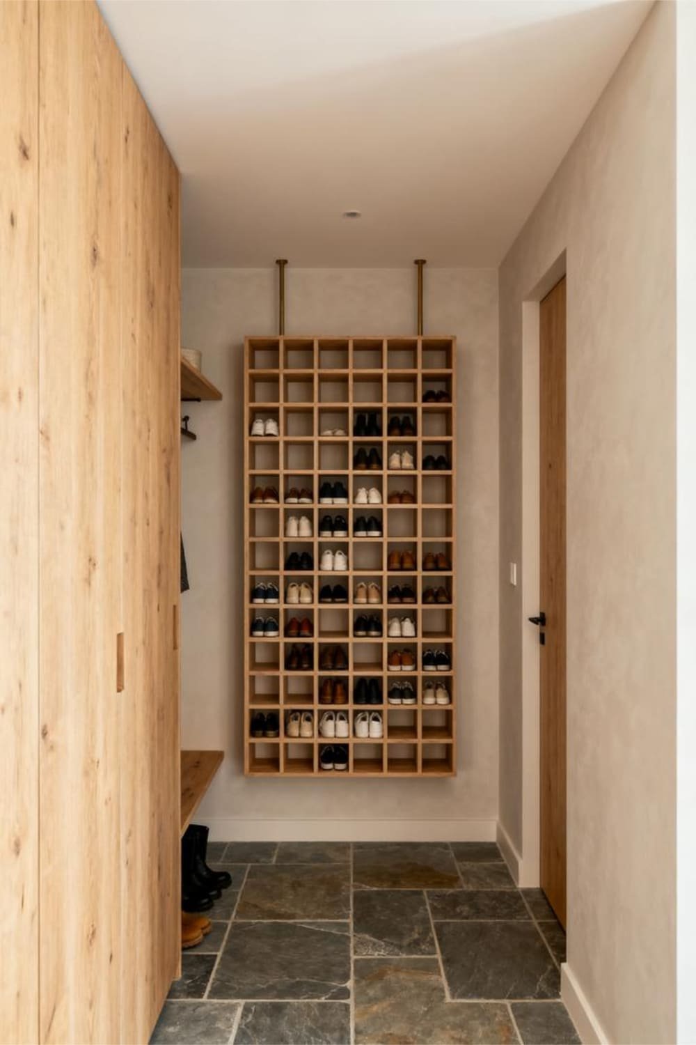 Wall-mounted shoe cubbies with organized pairs of shoes displayed in a light-wood grid system in a tidy mudroom.