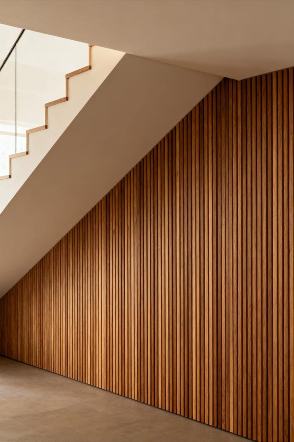 Vertical wood slat accent wall installed under a staircase.